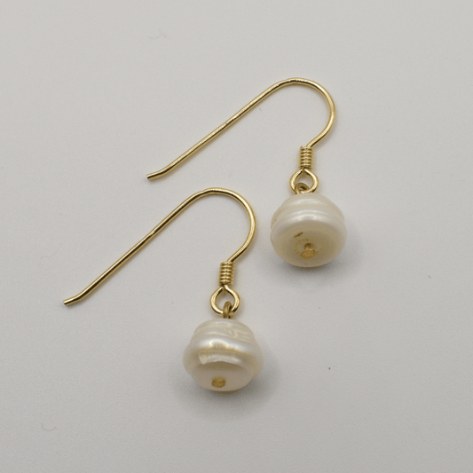 The Pearl earrings by Salty Dreamers feature a single irregular freshwater pearl on each gold earring, shown against a plain white background.