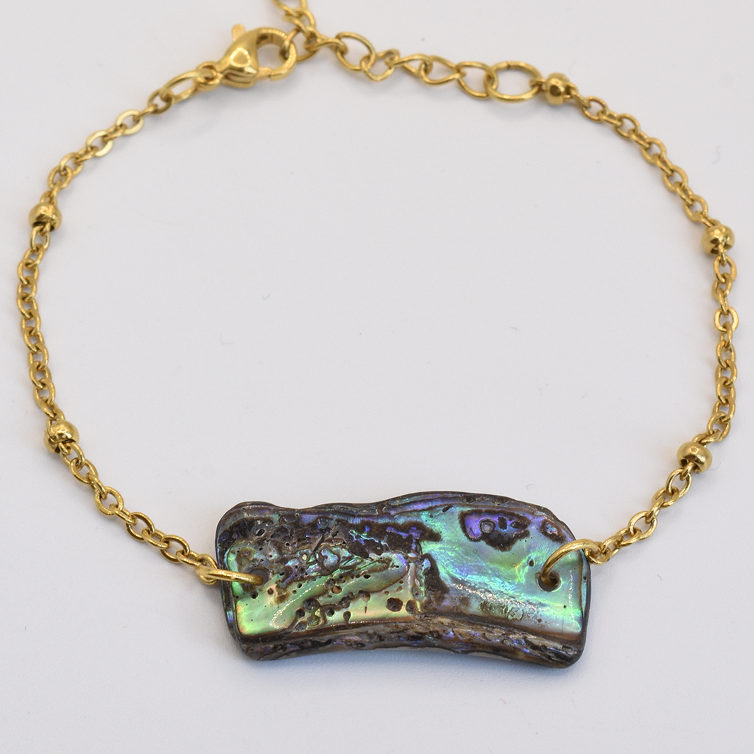 The Salty Dreamers Bracelet | Paua Shell Kiri features a gold chain and iridescent rectangular centerpiece with a lobster clasp—a beautiful piece of handmade New Zealand jewelry, shown on a white background.