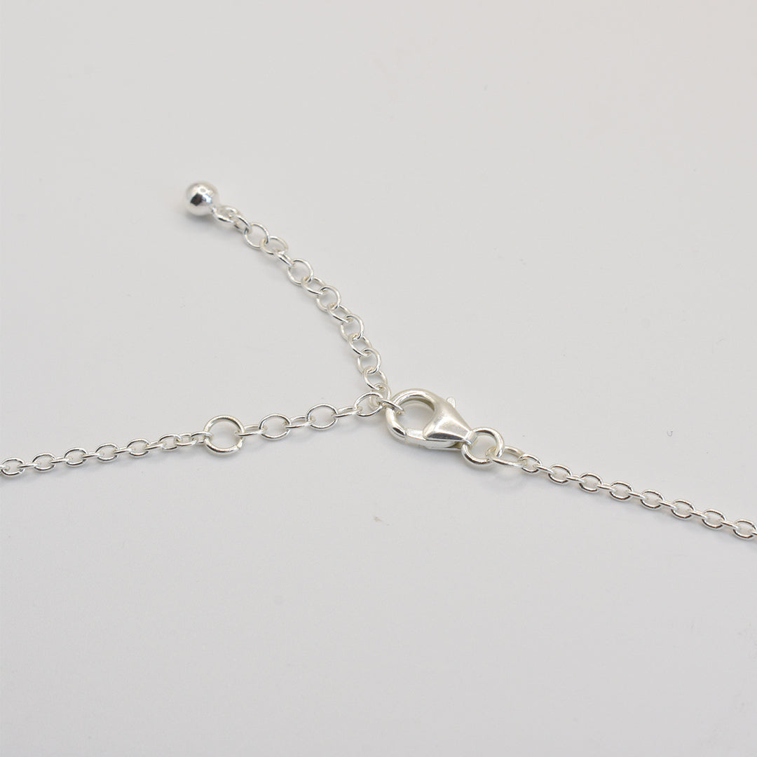 Close-up of Salty Dreamers Paua Shell Ruru necklace, handmade in sterling silver with a lobster clasp and adjustable links, shown on a plain white background.