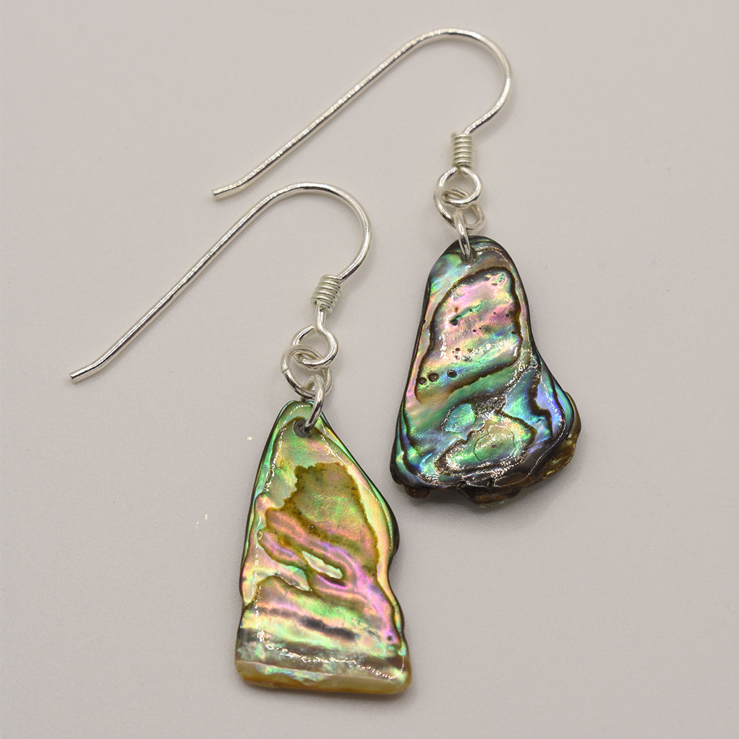 Salty Dreamers Earrings | Paua Shell Ruru: Handmade silver earrings with irregular, iridescent paua shell pendants and silver hooks, displayed on a light background.