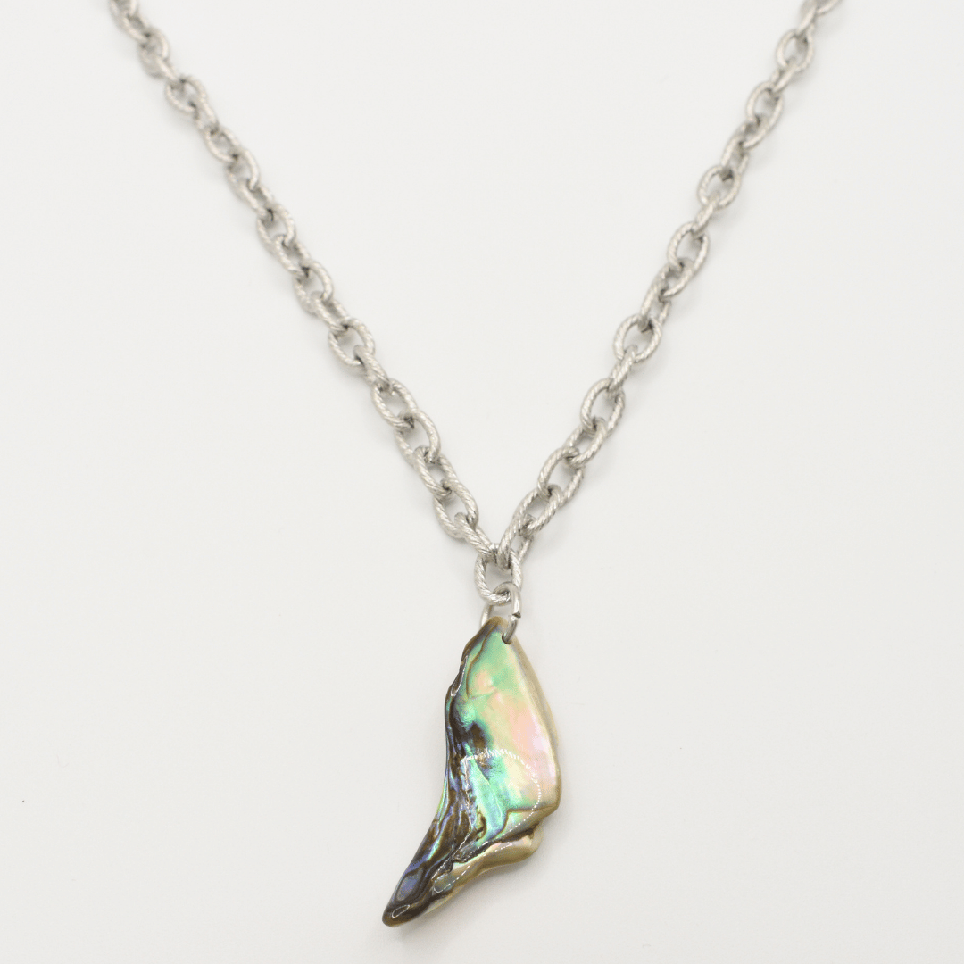 The Salty Dreamers Necklace | Paua Shell Hau is a silver stainless steel piece with a single iridescent pāua shell pendant, shaped like a small wing or shard, shown on a white background.