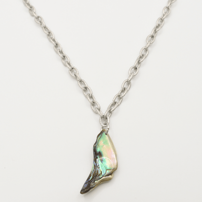 The Salty Dreamers Necklace | Paua Shell Hau is a silver stainless steel piece with a single iridescent pāua shell pendant, shaped like a small wing or shard, shown on a white background.