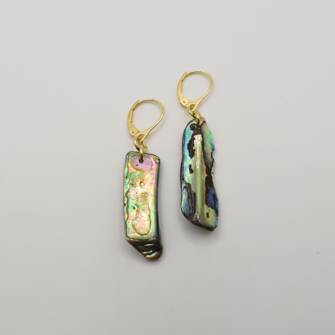 Salty Dreamers' "Earrings | Paua Shell One" are drop earrings with rectangular, iridescent New Zealand pāua shell pieces and gold hooks, shown on a plain white background.