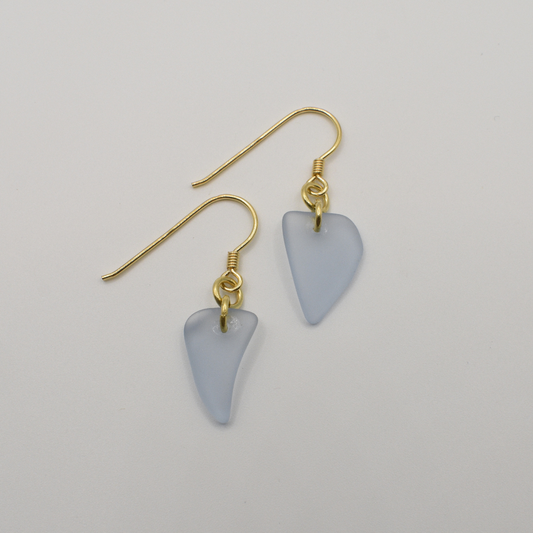 Salty Dreamers' Earrings | Seaglass Small Blue feature handmade, irregular triangle pendants made from translucent light blue seaglass and gold hooks, shown on a plain white background.