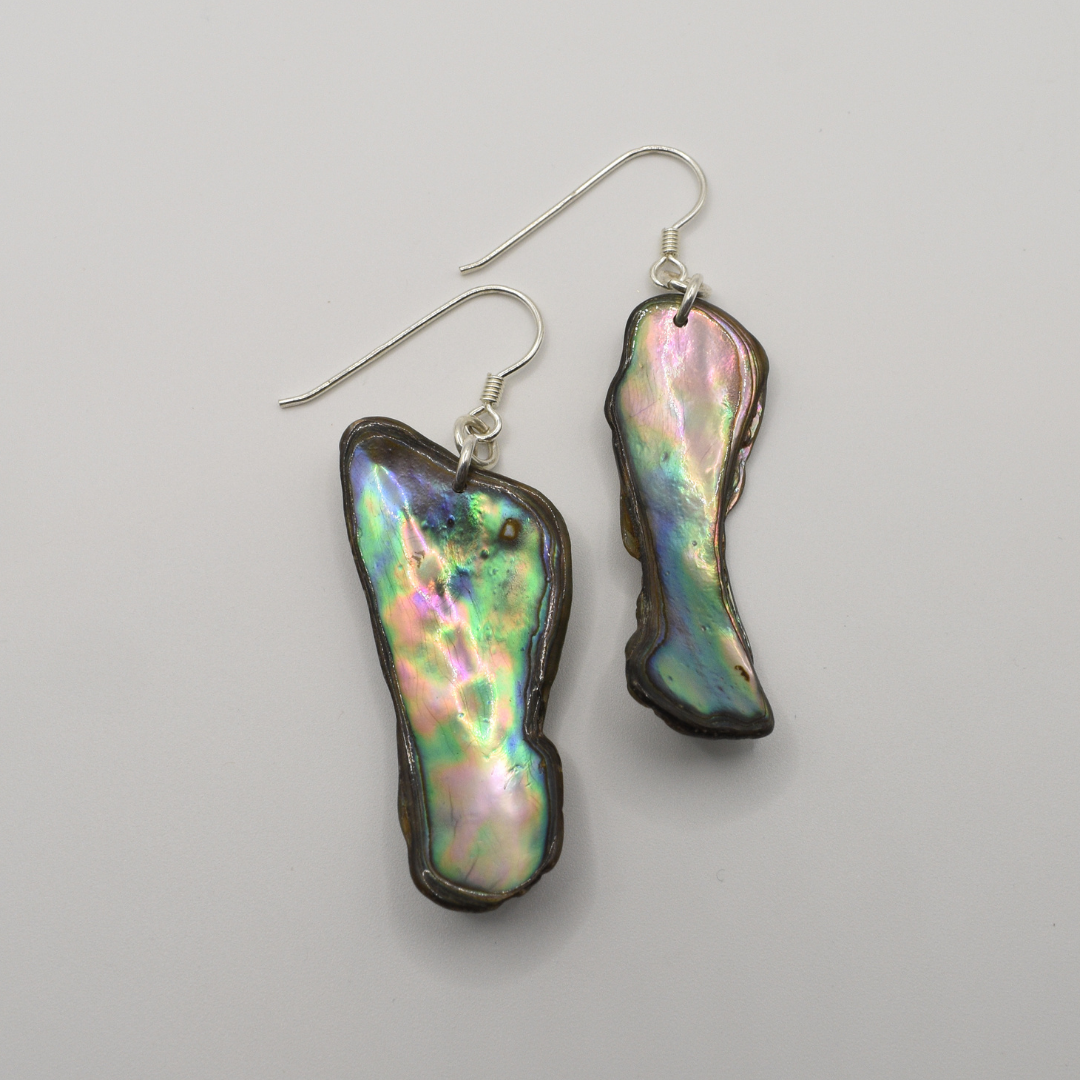 Salty Dreamers' Earrings | Paua Shell Aroha feature handmade, irregularly shaped iridescent paua shell pieces outlined in dark metal, shown on a plain white background.