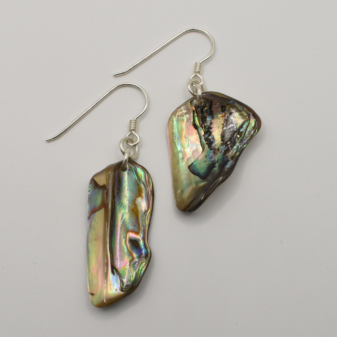 Salty Dreamers Earrings | Paua Shell Tieke feature handmade, irregularly shaped iridescent pāua shell pieces with silver hooks, shown against a plain white background.