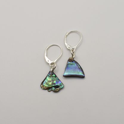 Salty Dreamers’ Earrings | Paua Shell Ngaru feature mismatched handmade earrings crafted from iridescent New Zealand abalone shell—one triangle, one irregular—set on silver lever-back hooks.