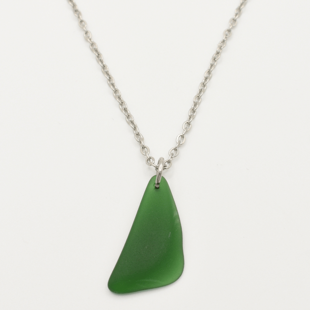The Salty Dreamers Necklace | Green Sea Glass features a unique, irregular green sea glass pendant on a silver chain—ideal for lovers of distinctive stainless steel jewelry.
