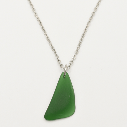 The Salty Dreamers Necklace | Green Sea Glass features a unique, irregular green sea glass pendant on a silver chain—ideal for lovers of distinctive stainless steel jewelry.