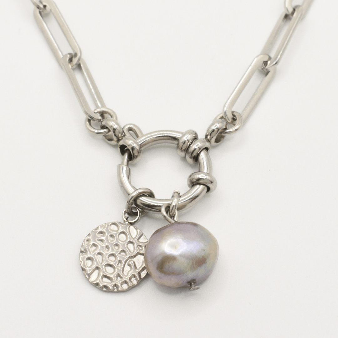 Salty Dreamers' A Cute Couple Pearl Necklace features a silver chain with large links, a circular textured charm, and a metallic lavender irregular freshwater pearl pendant on a hoop-like centerpiece.