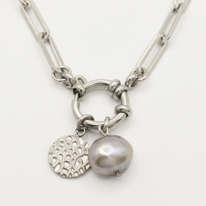 Salty Dreamers' A Cute Couple Pearl Necklace features a silver chain with large links, a circular textured charm, and a metallic lavender irregular freshwater pearl pendant on a hoop-like centerpiece.