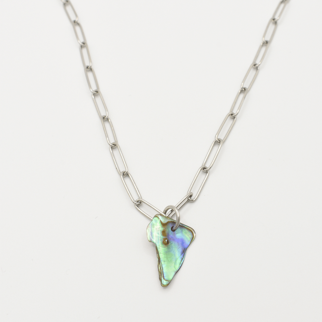 The Salty Dreamers Necklace | Paua Shell Pae features elongated silver links and an iridescent, irregular pāua shell pendant—handmade New Zealand jewelry displayed on a white background.