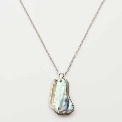 The Salty Dreamers Necklace | Paua Shell Kaukau features a handmade silver chain with an iridescent, uniquely-shaped paua shell pendant, shown on a white background.