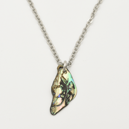 The Salty Dreamers Necklace | Paua Shell Takaro features a handmade silver chain with an irregular iridescent pāua shell pendant, displayed on a plain white background.