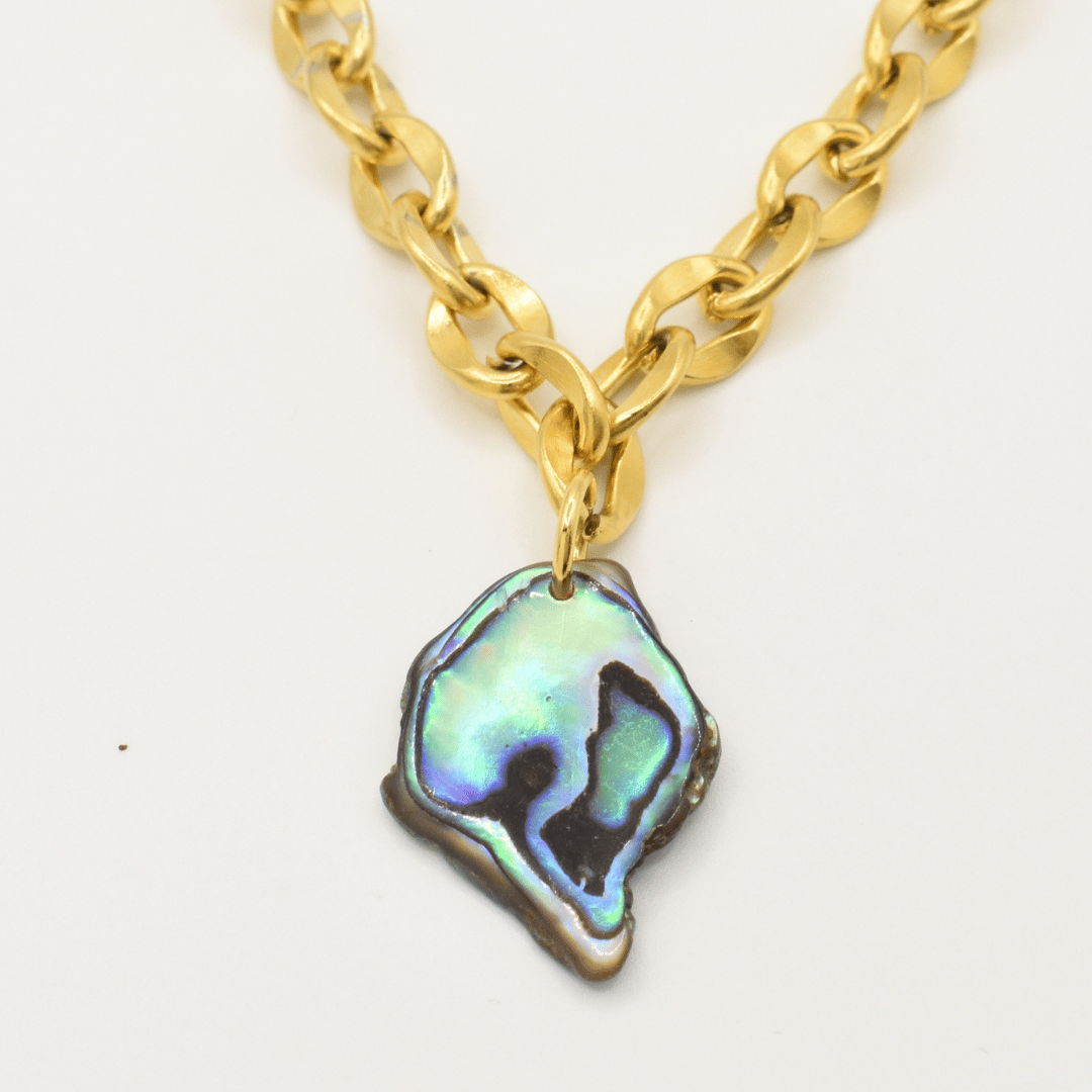 The Salty Dreamers Necklace | Paua Shell Tautahi features a chunky gold chain and a handmade abalone pendant with an iridescent, irregular pāua shell showcasing stunning blue, green, and black hues.