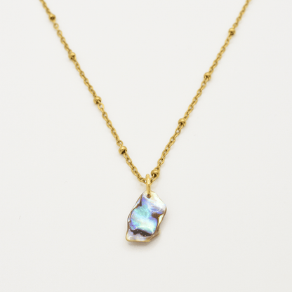 The Salty Dreamers Necklace | Paua Shell Ra features a golden stainless steel beaded chain and an iridescent, irregularly shaped paua shell pendant, shown centered against a plain white background.