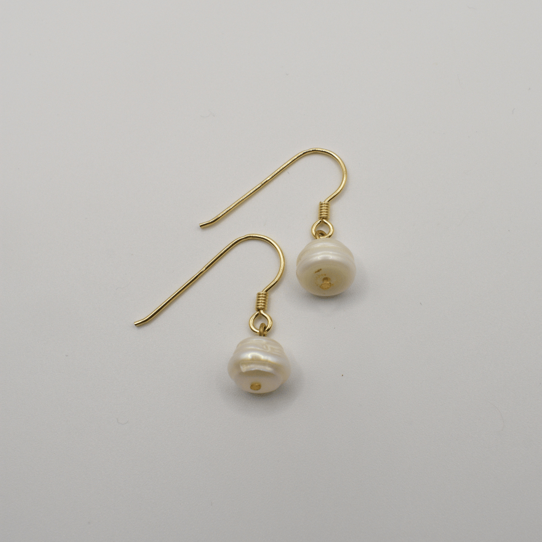 The Pearl earrings by Salty Dreamers feature handmade gold settings with irregular freshwater pearl drops, shown on a plain white background.