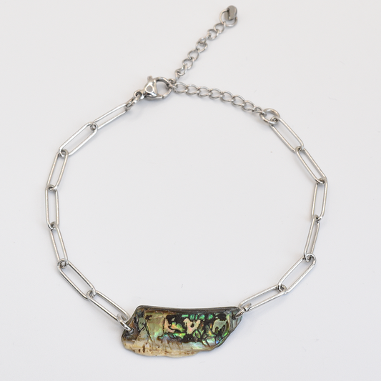 The Salty Dreamers Bracelet | Paua Shell Raumati features elongated handmade silver links and an iridescent, irregular New Zealand paua shell centerpiece, shown on a white background.