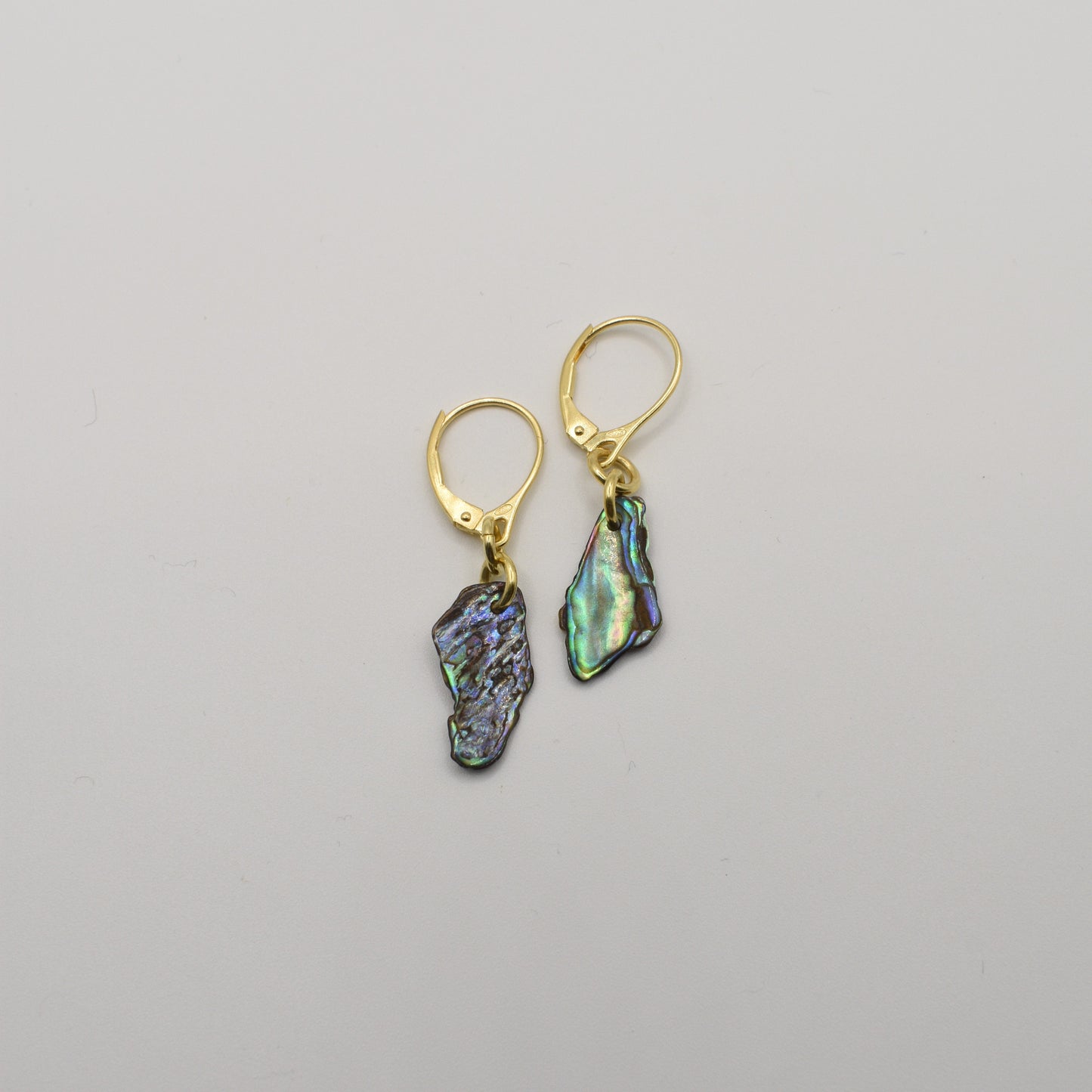 Salty Dreamers' Paua Shell Moana Earrings are handmade gold leverbacks featuring irregular iridescent abalone shell pendants, shown on a plain white background.