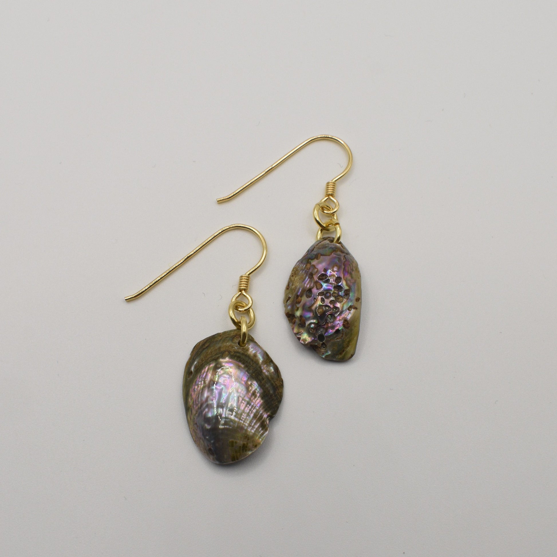 Salty Dreamers Earrings | Paua Shell Mahaki are gold-plated silver hook earrings with iridescent oval pāua shell pendants, shown on a plain white background—an elegant handmade accessory for any occasion.