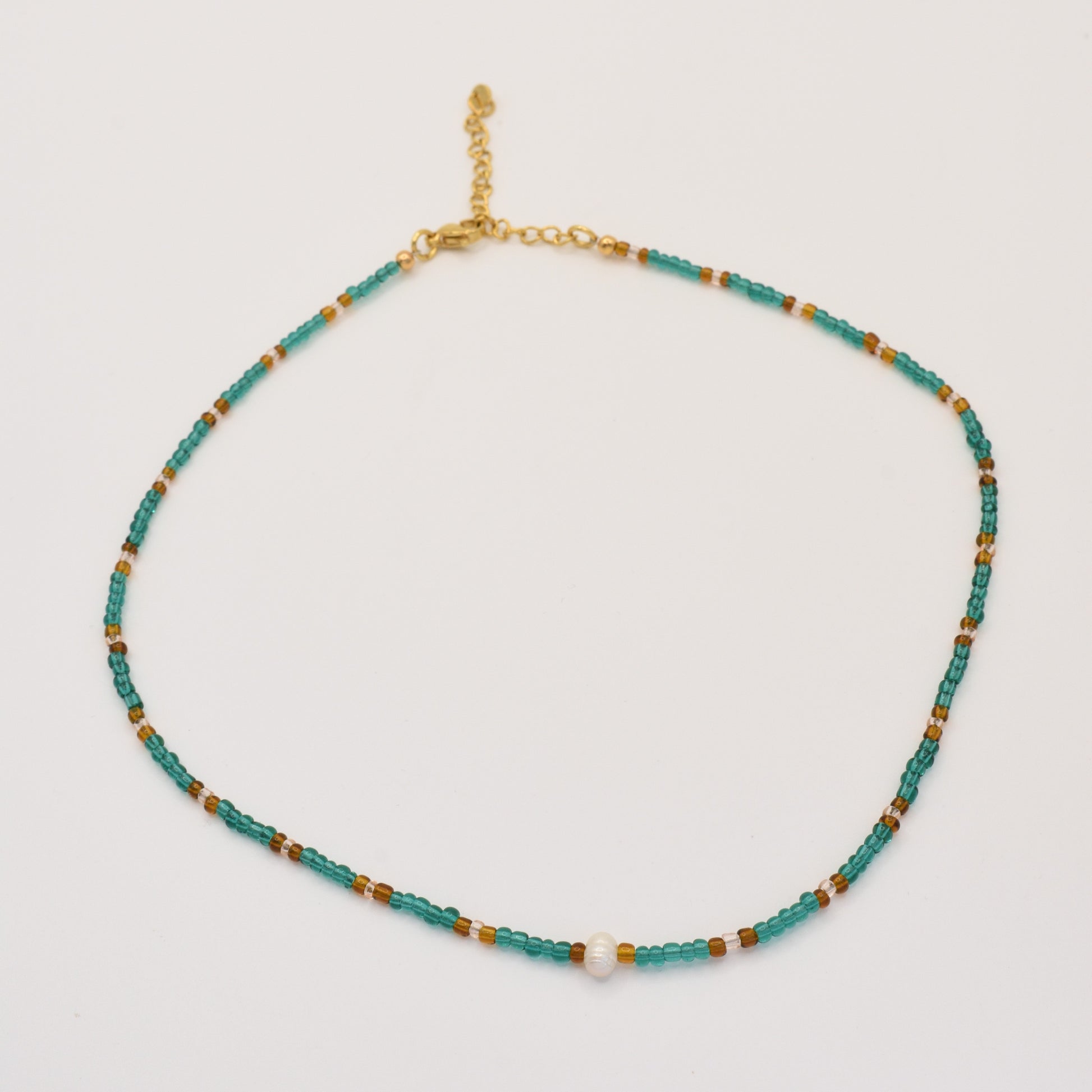 The Necklace | Fresh Beads Blue by Salty Dreamers is a handmade piece featuring turquoise, brown, and gold beads with a central freshwater pearl and an adjustable gold chain clasp, displayed on a white background.