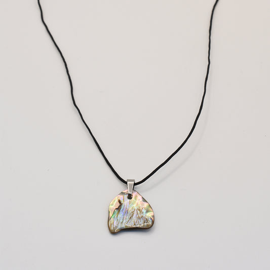 The Necklace | Paua Shell Whitau by Salty Dreamers is a handmade piece featuring an irregular, iridescent pāua shell pendant on a thin waterproof nylon cord with a silver bail—unique ocean jewelry.