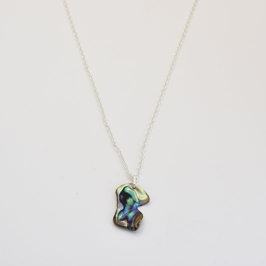 The Salty Dreamers Necklace | Paua Shell Kea is a handmade silver necklace with an irregular, iridescent pāua shell pendant, shown against a plain white background.