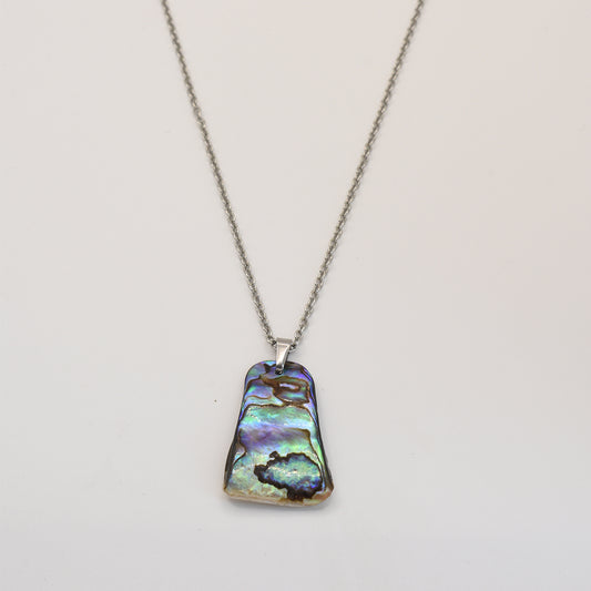 The Salty Dreamers Necklace | Paua Shell Whenua features a silver stainless steel chain with a rectangular, iridescent New Zealand paua shell pendant in blue, green, and purple tones, shown on a plain white background.