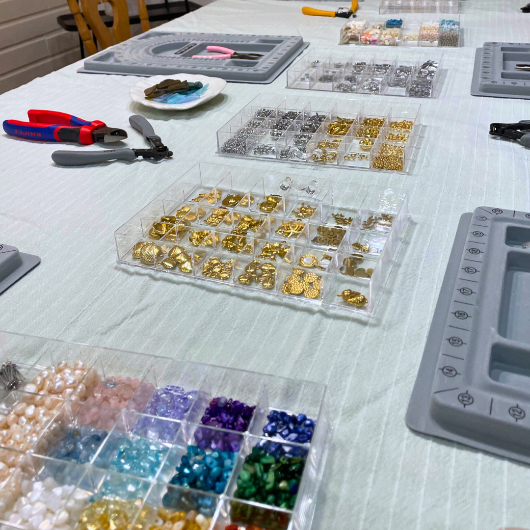 At Salty Dreamers' Workshop Ocean Jewellery in Kiel, a white-clothed table displays colorful beads, charms, tools, and bead boards—everything you need to create your own ocean jewellery.