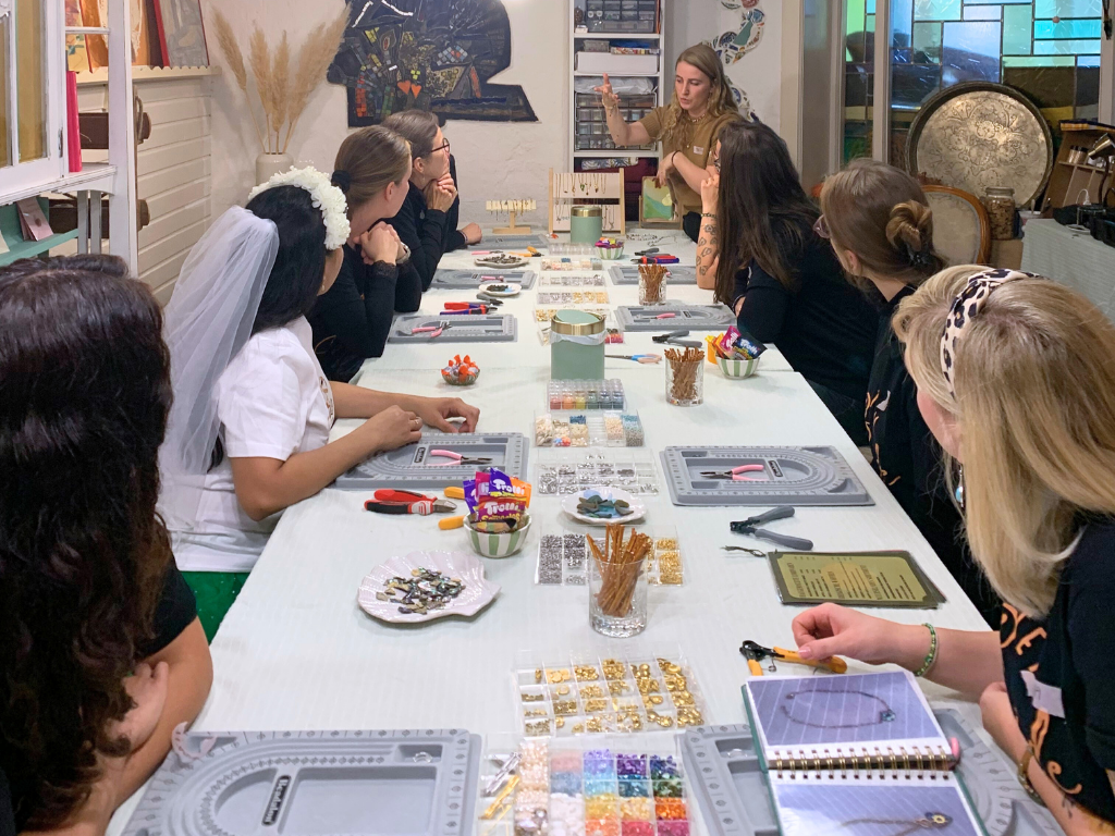 Group of people at a craft workshop with materials on a long table.