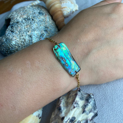 a golden abalone shell bracelet on wrist